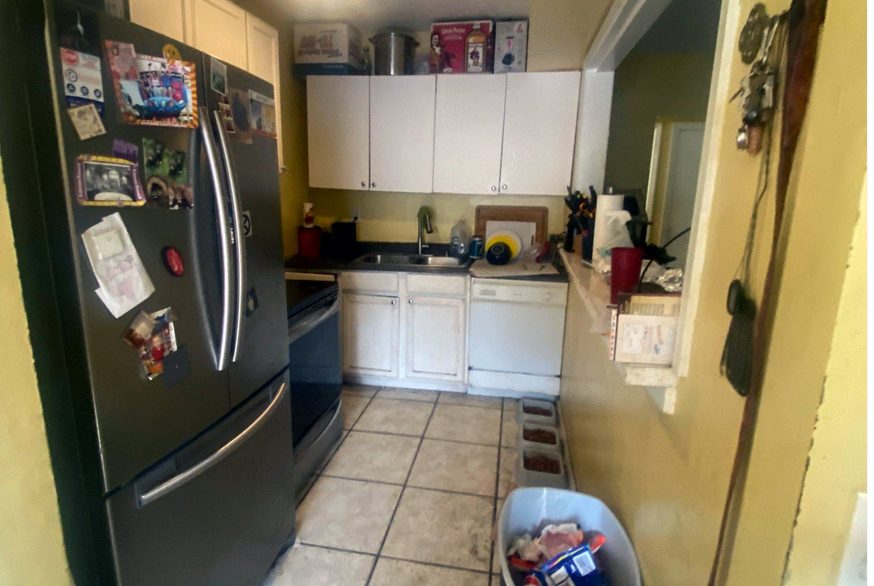 Before: dated galley kitchen with worn white cabinets, laminate counters and yellow walls
