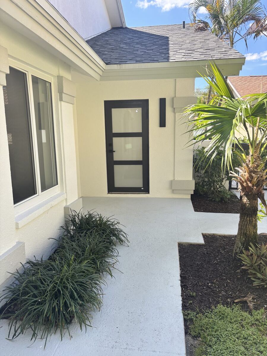 After: Jupiter home in The Bluffs repainted a light exterior with a black glass front door, new entry walkway and landscaping
