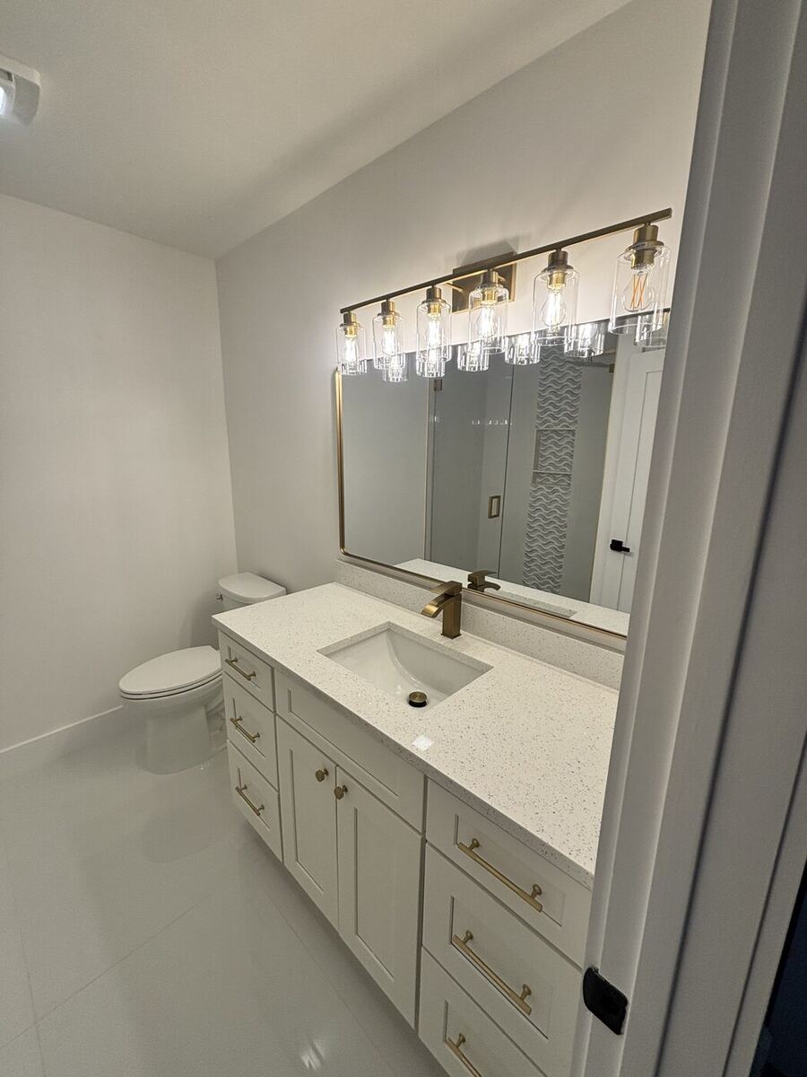 Guest bath with white shaker vanity, quartz top and new vanity light