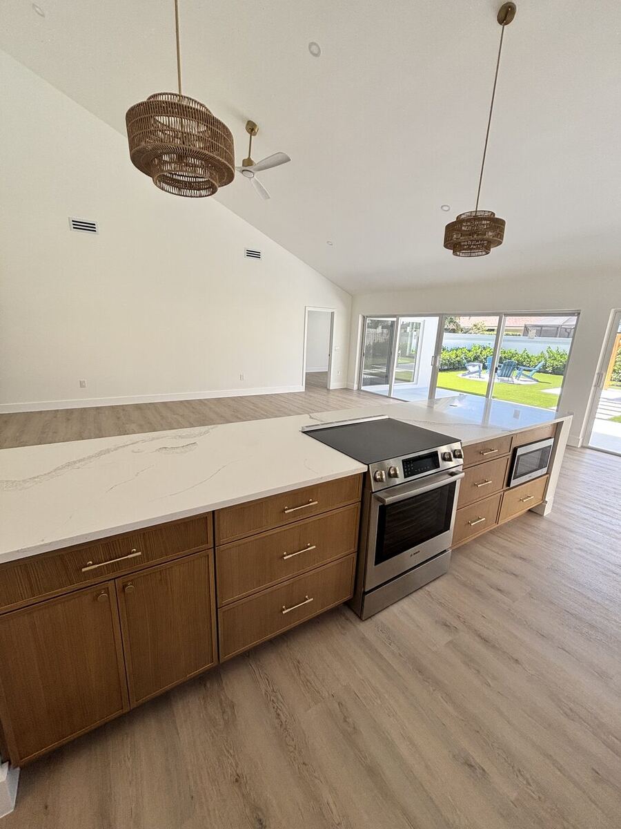 Wood-front island base with quartz top facing a stainless steel range
