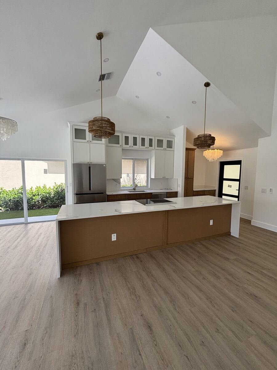 Open kitchen under a vaulted ceiling with woven pendant lights and a quartz-topped island